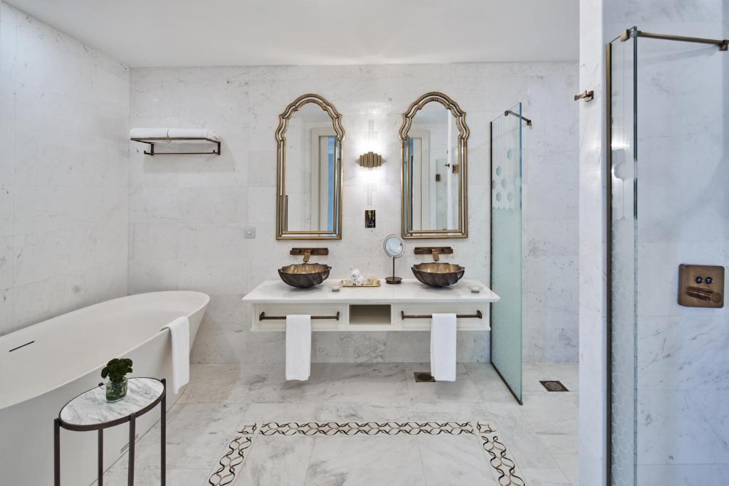 Mūsdienīgs un elegants vannas istabas interjers ar marmora sienām, diviem spoguļiem, divām vannas izlietnēm un brīvi stāvošu vannu. Izsmalcināta apgaismojuma un modernu detaļu kombinācija.