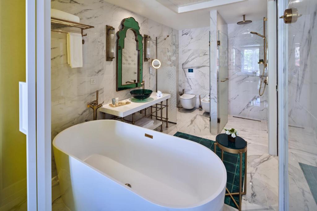 Moderns vannas istabas dizains ar marmora sienām, elegantu brīvo vannu un zaļā krāsā akcentiem. Interjers ietver modernus santehnikas risinājumus un stilīgu apgaismojumu.