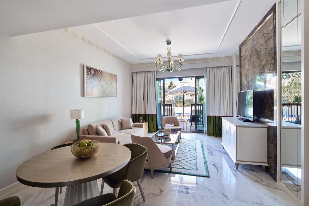 Mūsdienīgs viesnīcas numurs ar dzīvojamo zonu, ērtām mēbelēm un piekļuvi terasei. Interjers ir elegants ar baltām un zaļām krāsām, kas rada patīkamu atmosfēru.