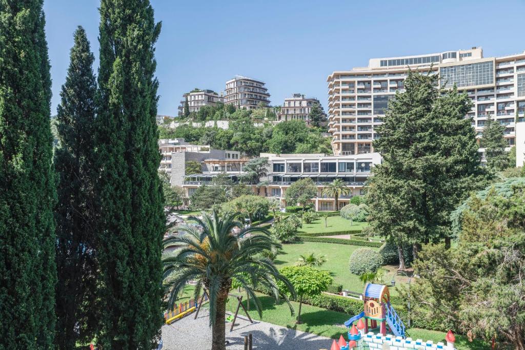 Ainava ar zaļām palmu un cipresēm, kas izceļ modernu apbūvi kalnos un labi kopta parka teritoriju. Mierīga atmosfēra ar bērnu spēļu laukumu.