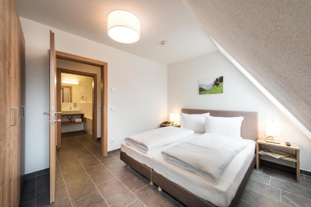 Mūsdienīga viesnīcas numura interjers ar divguļamo gultu, koka skapjiem un piekļuvi vannas istabai. Gaisma no griestu lampas un naktslampām rada ērtu atmosfēru.