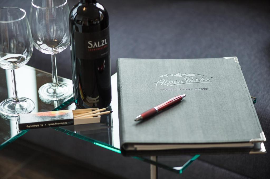 Vīna pudele kopā ar glāzēm un ēdienu izvēles grāmatu, kas novietota uz stikla galda. Ideāls romantiskai vai svinīgai atmosfērai.