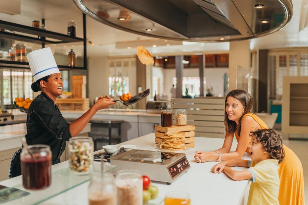 Viesnīcas Tamassa Bel Ombre šefpavārs gatavo pankūkas, priecīgas vieses un bērns.