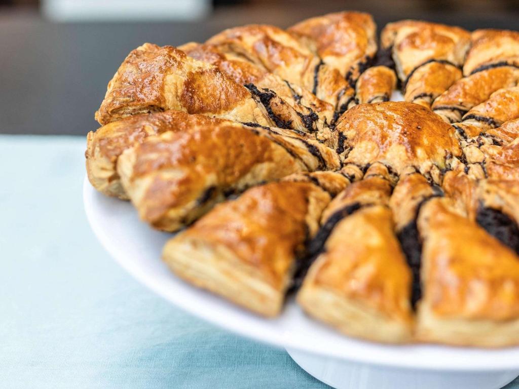 Svaiga un zeltaina kūka ar šokolādes pildījumu, pasniegta uz balta šķīvja. Idealizēta desertu prezentācija, kas piesaista uzmanību un izsaka mājīgumu.
