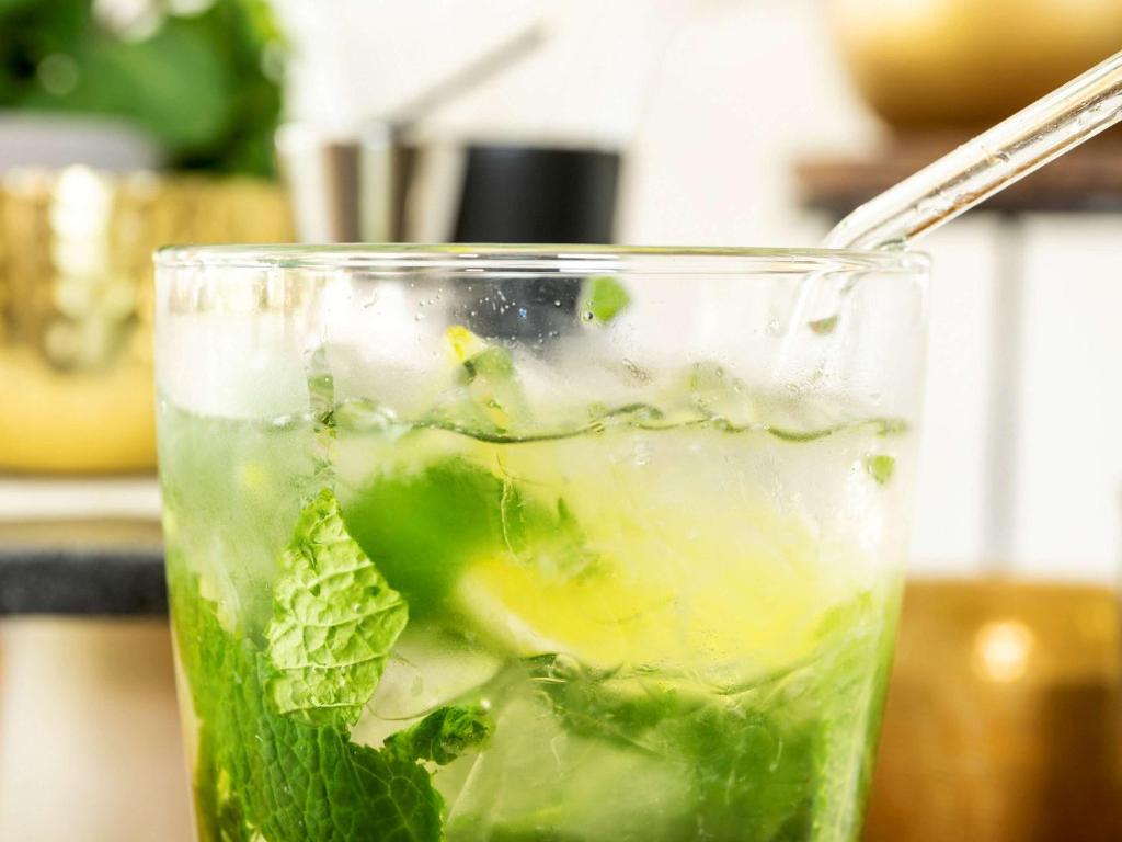 Atsvaidzinošs kokteilis ar piparmētru un laimi, pasniegts glāzē ar salmiņu. Dzēriens ir dzidrs un aromātisks, radot atsvaidzinošu noskaņu.