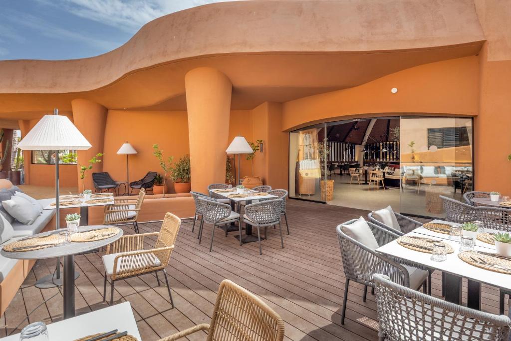 Mūsdienīga terase ar elegantiem galdiem un krēsliem, ko ieskauj siltas oranžas sienas un dabiski augi. Ideāla vieta relaksācijai un maltītēm brīvā dabā.