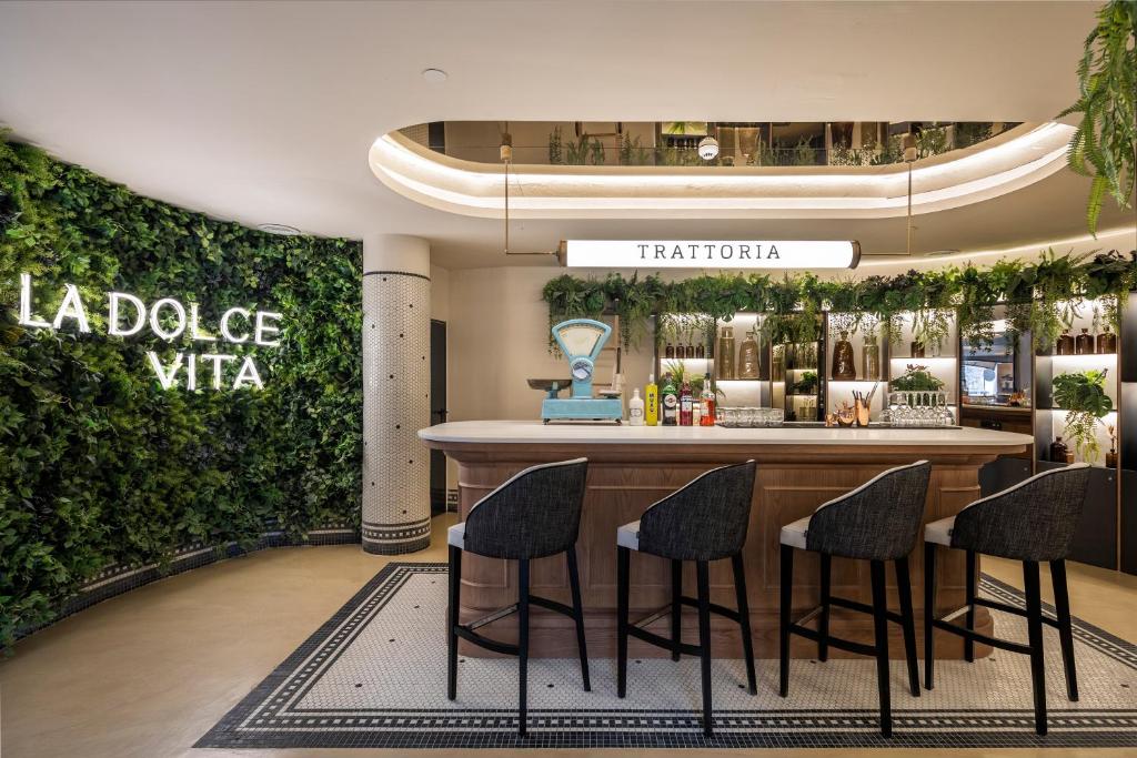 Mūsdienīgs bārs ar zaļām dekorācijām un elegantu interjeru, kurā redzama zīme 