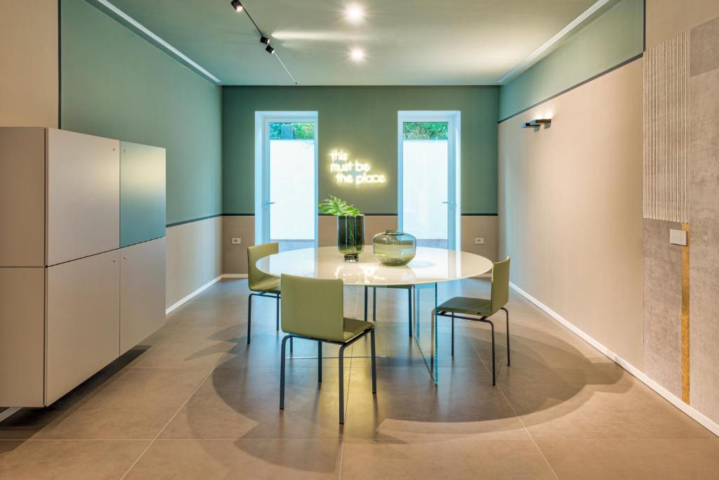 Mūsdienīga ēdamistaba ar apaļu galdu un krēsliem, gaiši zaļas sienas.
