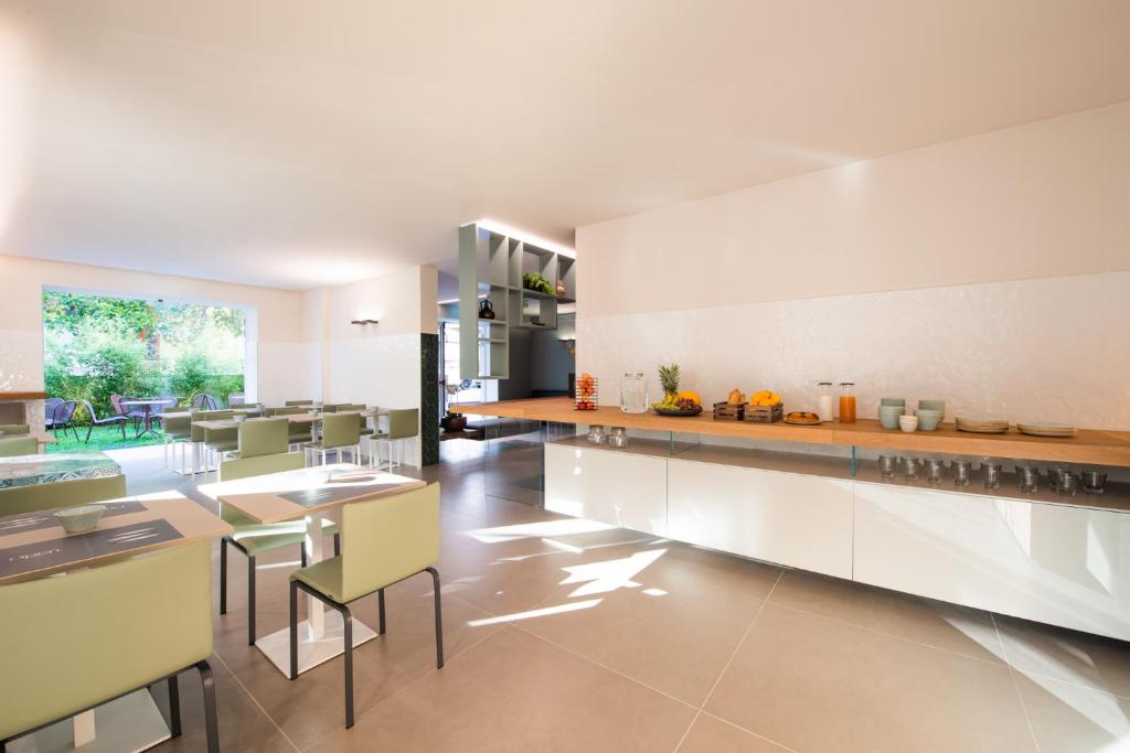 Gaiša un moderna viesnīcas brokastu zona ar dārzu skatu.