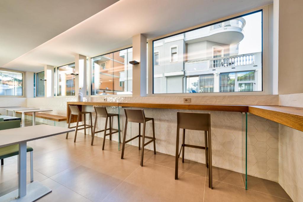 Modernā restorāna interjers ar koka galdu un krēsliem, lieli logi ar skatu uz ielu.