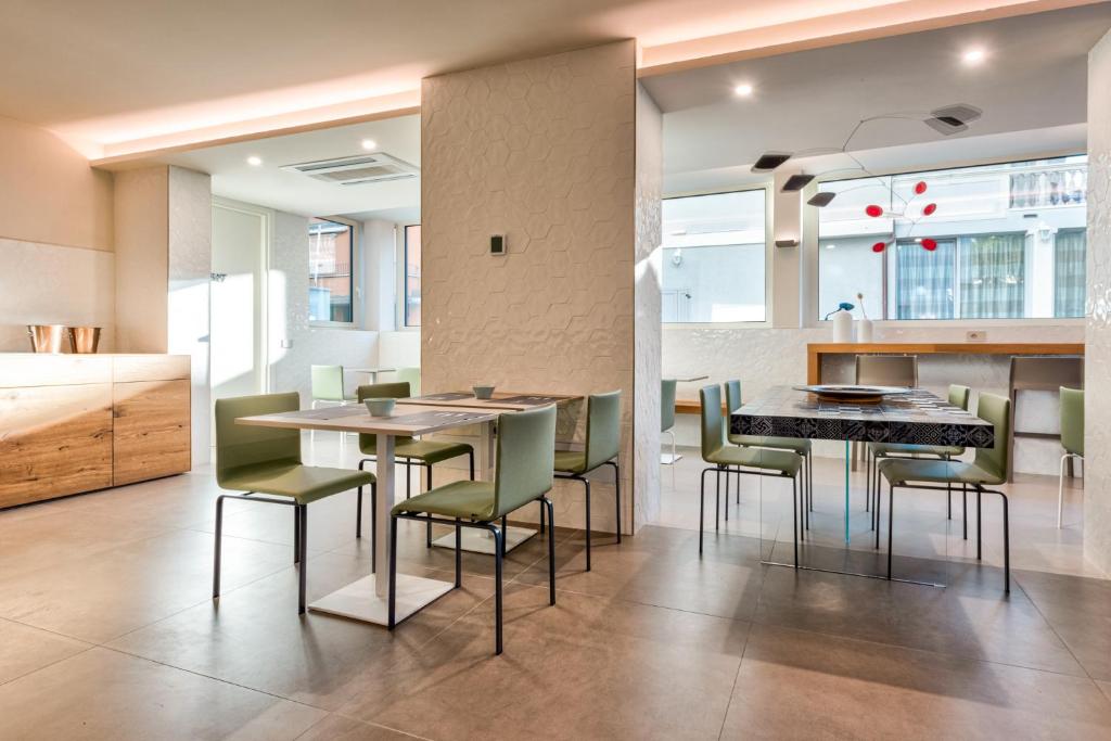 Mūsdienīgs ēdamgalds ar zaļām krēsliem un koka skapīti viesnīcas restorānā.