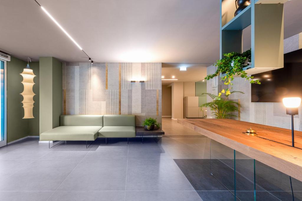 Mūsdienīgs viesnīcas reģistratūras interjers ar zaļo dīvānu un dekoratīvām lampām.
