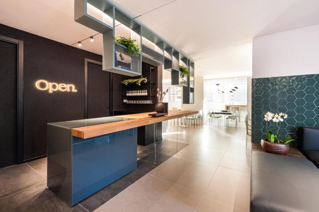 Mūsdienīgs viesnīcas reģistratūras interjers ar 'Open' zīmi.
