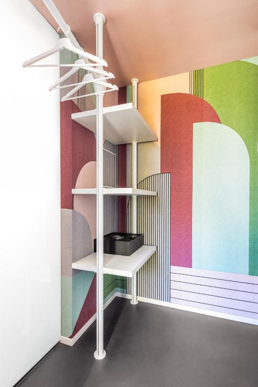 Moderna drēbju skapis ar krāsainu sienu un plauktiem.