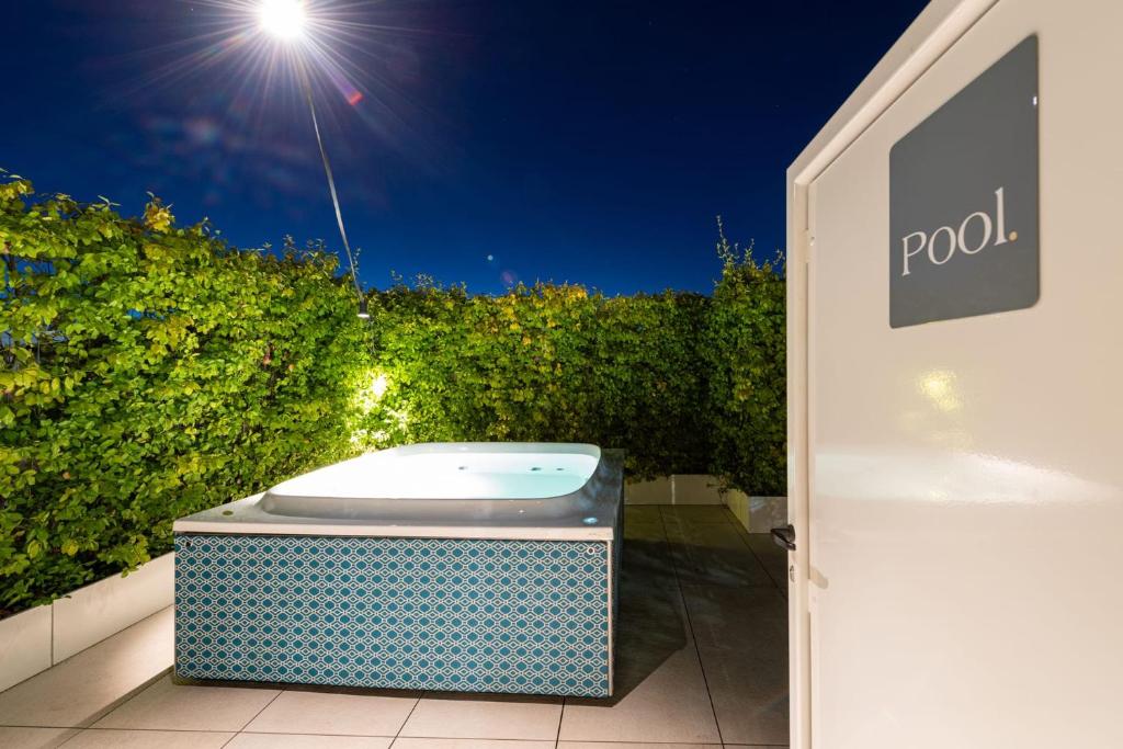 Nakts skats uz jacuzzi un apgaismotu peldbaseinu, apkārt zaļajām dzīslām.