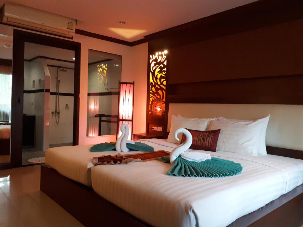 Mūsdienīgs numurs Chivatara Resort Bangtao ar divām gultām un dekoratīviem dvieļiem.
