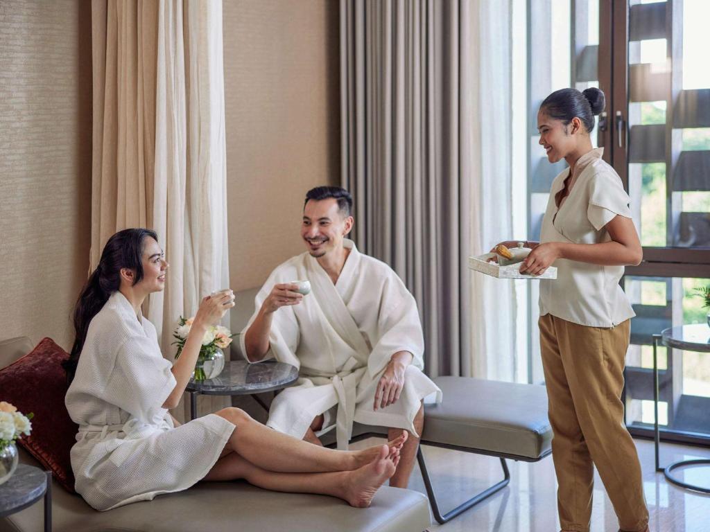Spa atmosfērā divi cilvēki baudījuši relaksāciju un dzērienus, kamēr apkalpojošais personāls pasniedz uzkodas.
