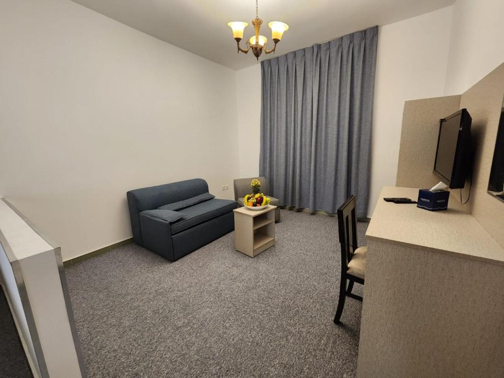 Mūsdienīga viesistaba ar pelēku dīvānu, galdu un ērtu krēslu, apgaismota ar lustru un ar aizkariem. Interjers ir vienkāršs un elegants, radot mājīgu atmosfēru.