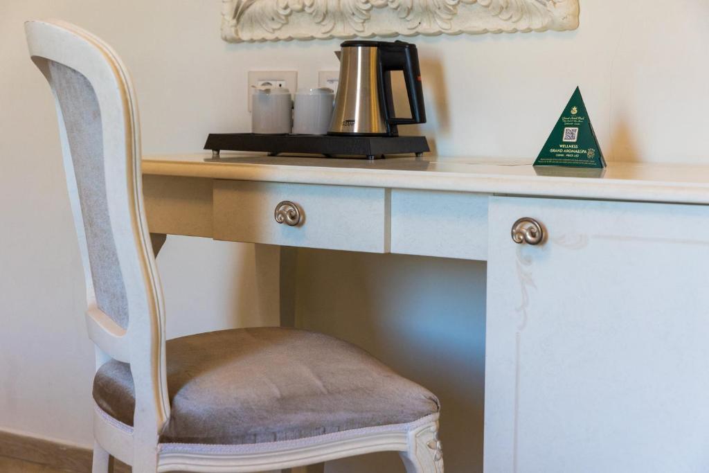 Elegantā galda un krēsla izkārtojums ar tējkannu un informācijas stendu par wellness pakalpojumiem.