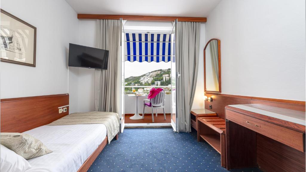 Gaisma un moderna viesnīcas istaba ar balkonu, no kura paveras skaists skats uz apkārtni. Istabā ir televizors, vienkāršs mēbeļu komplekts un ērta gulta.