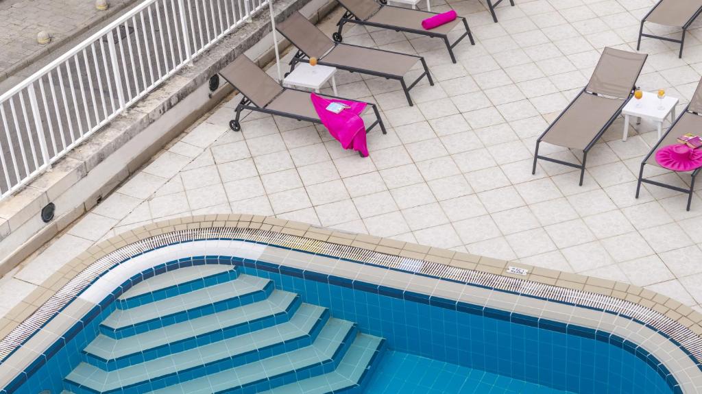 Baseins ar pakāpieniem, ap to izvietoti sauļošanās krēsli un galdi. Apkārtne ir klātas ar flīzēm, radot relaksējošu atmosfēru.