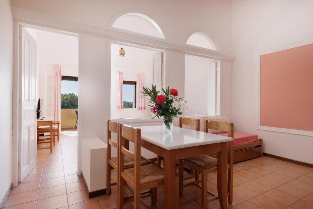 Gaišs un mājīgs interjers ar koka galds un krēsliem, kas rotāti ar ziedu pušķi. Logi ar rozā aizkariem piedāvā skatu uz ārpusi.