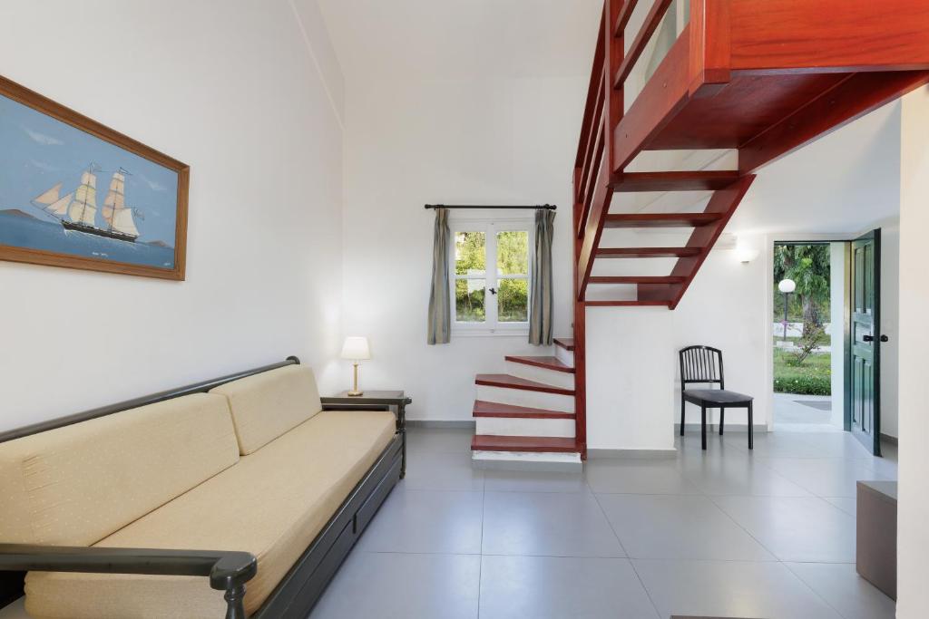 Mūsdienīgs dzīvojamais istabas interjers ar dīvānu, koka kāpnēm un gleznainu skatu uz dārzu. Telpa apgaismota ar dabiskiem gaismas avotiem un dekorēta ar jūras motīvu.