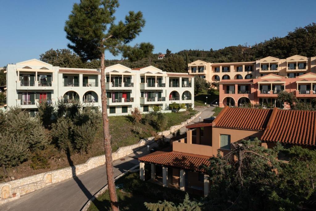 Mūsdienīga viesnīcas kompleksa ainava ar vairākām ēkām un zaļām zonām, kas atrodas kalnainā apvidū. Viesnīcas fasādes ir krāsainas, un tās ir ieskautas dabā.