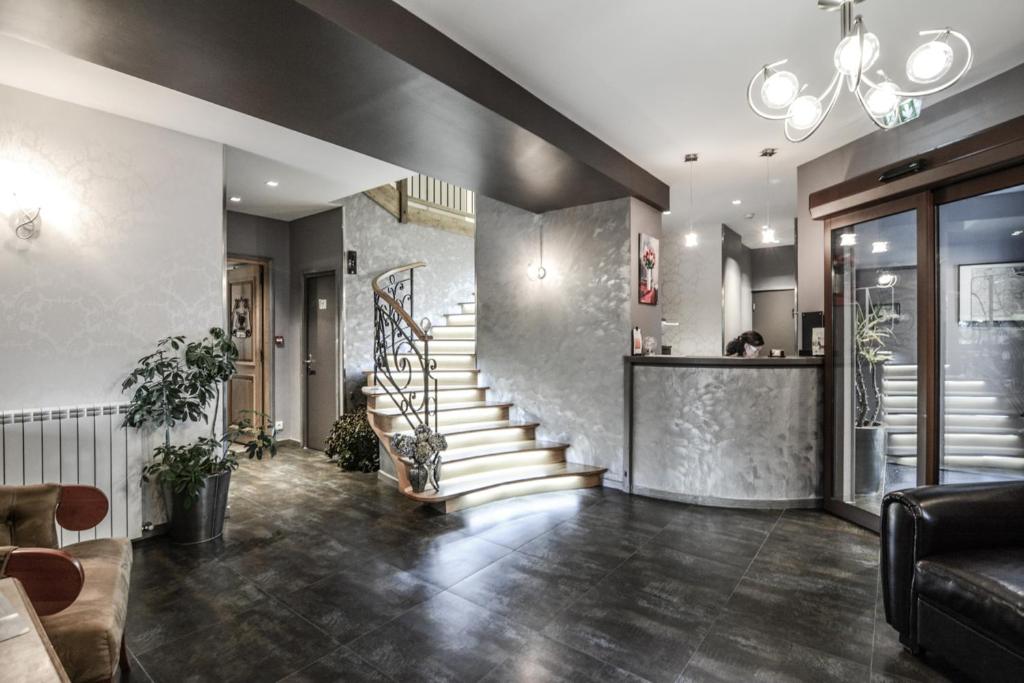 Moderns viesnīcas reģistratūras interjers ar elegantu kāpņu telpu un stilīgu apgaismojumu. Telpa ir iekārtota ar augstas kvalitātes materiāliem un augiem, radot patīkamu atmosfēru.
