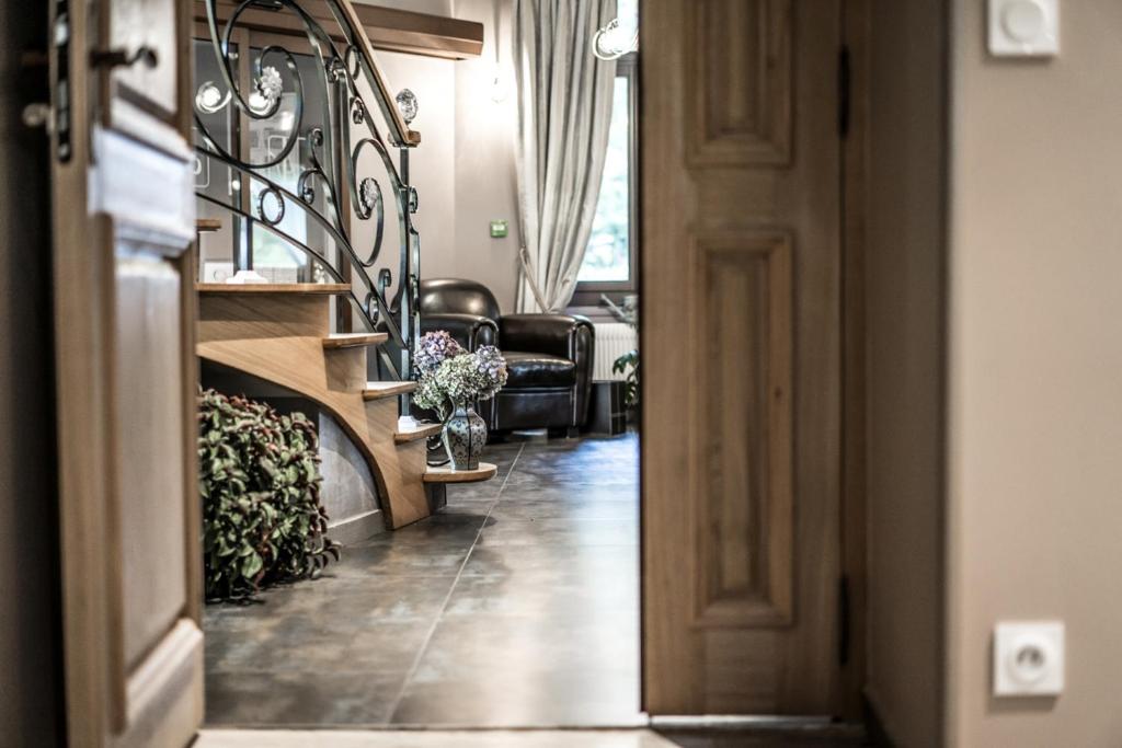 Mūsdienīga mājas interjera aina ar koka kāpnēm un elegantiem aksesuāriem, kas rada siltu un viesmīlīgu atmosfēru. Svaigi ziedi un mājas augu klātbūtne pievieno dabīgu šarmu.