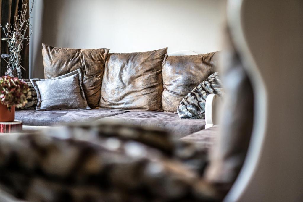 Mūsdienīgs dīvāns ar spilveniem, kas izceļ eleganci un komfortu, papildināts ar dekoratīvām zālēm. Interjers rada mājīgu atmosfēru.