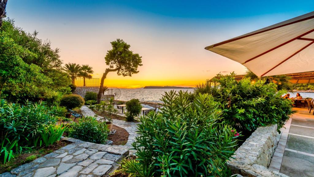 Skaists saulriets pār pludmales dārzu, kur aug zaļumi un ziedi, un redzama terase ar ēdināšanas zonu.