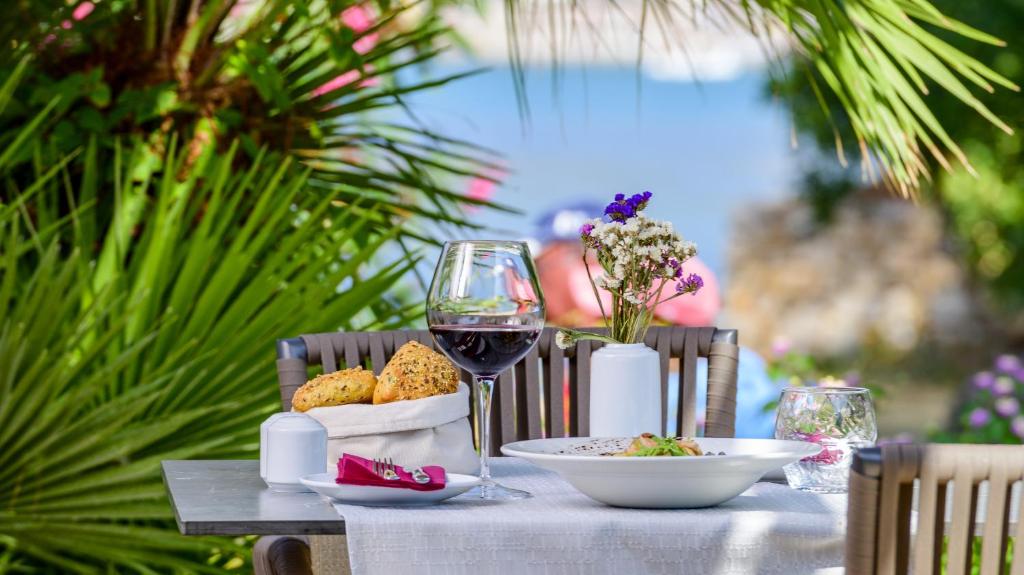 Galda klāšana ar sarkano vīnu un ēdienu, ko rotā ziedi, ieguvusi mierīgu pludmales fonu. Ideāla atmosfēra relaksējošai maltītei brīvā dabā.
