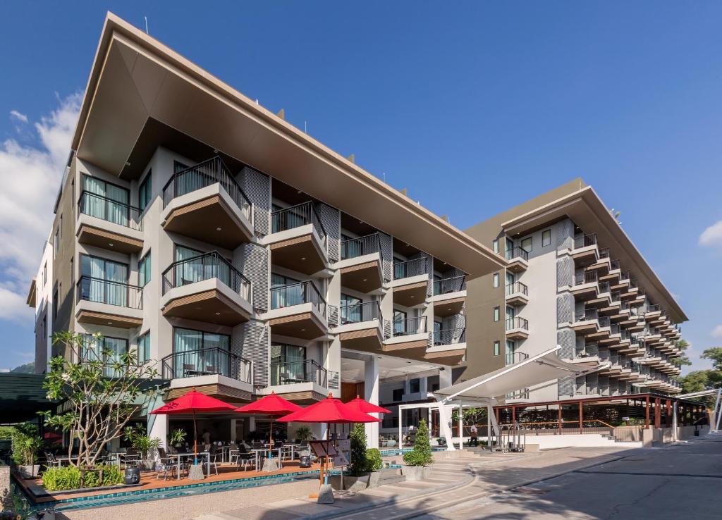 Mūsdienīga viesnīca ar plašām balkonu terasēm un sarkaniem saulessargiem, kas atrodas ērtā vietā. Viesnīca ir ieskauta zaļumiem un piedāvā mūsdienīgu arhitektūru.