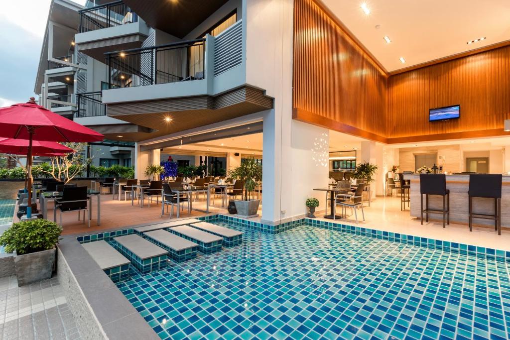 Moderns viesnīcas restorāns ar peldbaseinu un terasi, kas aprīkota ar ērtām galdiem un krēsliem, piedāvā relaksējošu atmosfēru. Sarkanās saulessargu un zaļo augu akcenti piešķir vietai dzīvīgumu.