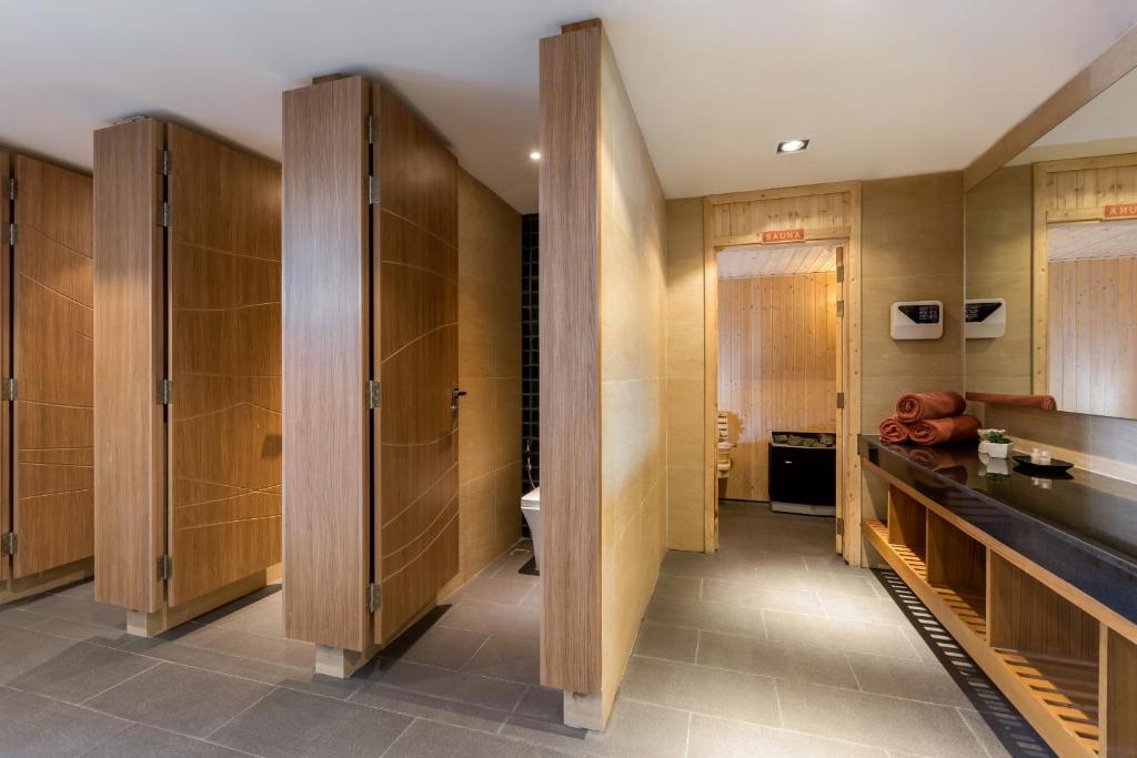 Mūsdienīga pirts telpa ar koka starpsienām, akmens grīdu un gaišām sienām. Skats uz pirts durvīm un tām piegulošo zonu.