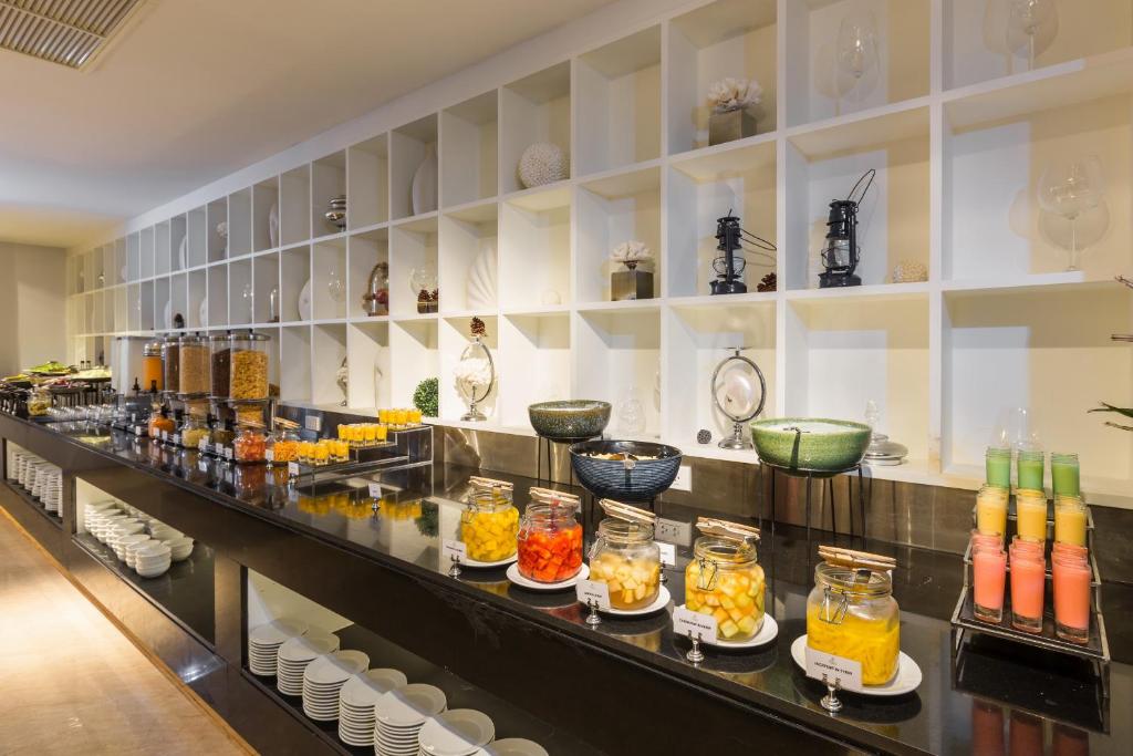 Pusdienu bufete ar dažādām augļu un dzērienu izvēlēm, kā arī dekoratīvām detaļām. Stends ir sakārtots ar glītiem traukiem un stikla burkām.