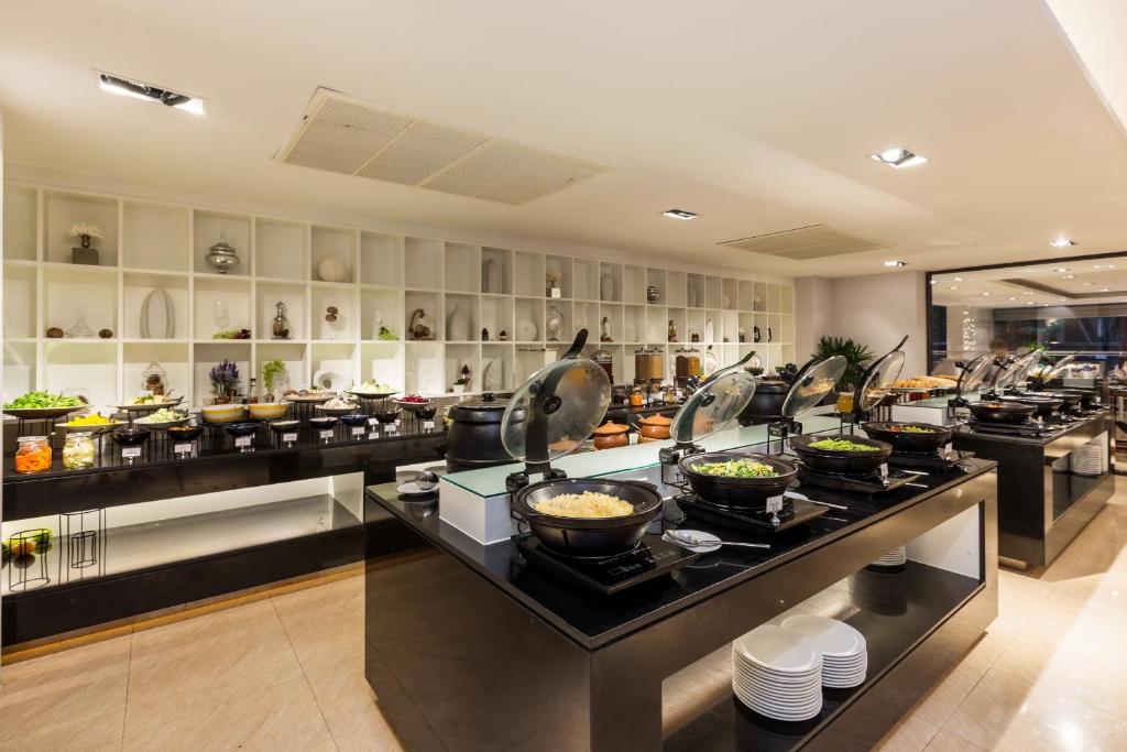 Bufetes stils ar dažādiem ēdieniem un salātiem, izvietoti uz melna galda, ar gaišu interjeru un dekoratīvām detaļām fona.