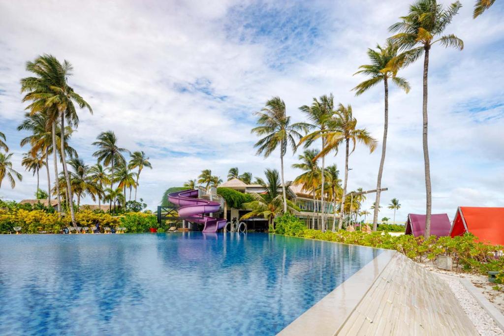 Tropu pludmales kūrorts ar zilu baseinu un violetu ūdens slidkalniņu, ko ieskauj palmas un sulīga zaļumi. Ideāla vieta atpūtai un izklaidei.