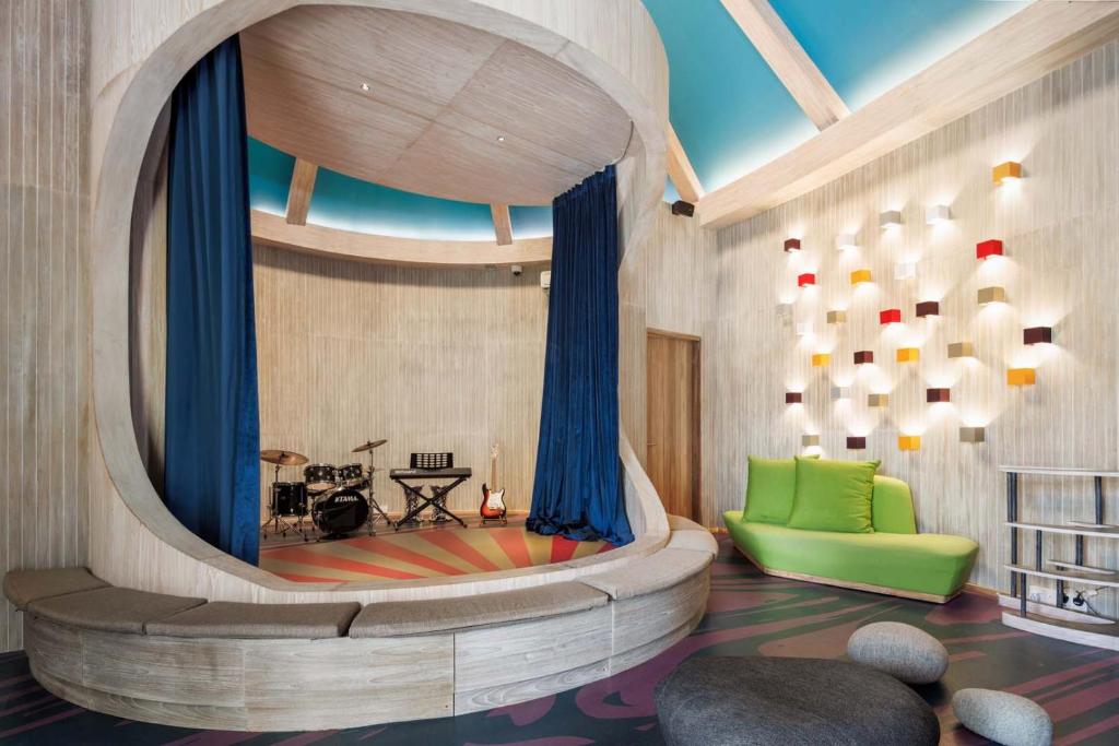 Moderns, daudzfunkcionāls telpas dizains ar skatuvi un ērtu atpūtas zonu, kas iekārtota ar spilgtām krāsām un mūzikas instrumentiem. Gaismas elementi piešķir telpai radošu atmosfēru.