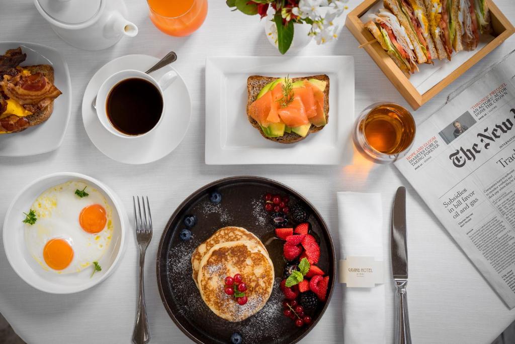 Pusdienu galds ar pankūkām, olu, sviestmaizēm un kafiju, ko papildina augļu un ziedu dekorācijas. Ideāls brīdis, lai izbaudītu gardas brokastis.