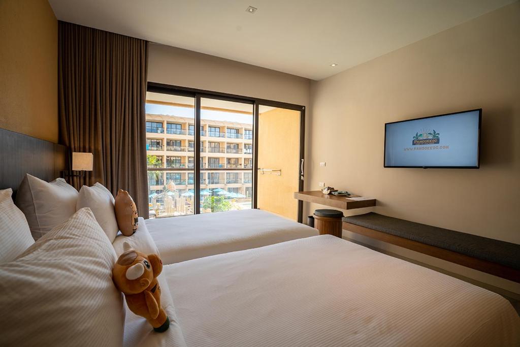 Mūsdienīgs viesnīcas numurs ar divām gultām, skatu uz baseinu un TV. Interjerā ir neitrālas krāsas un mājīgs dekors.