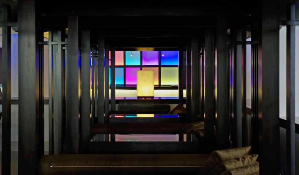 Mūsdienīga interjera telpa ar melniem koka elementiem un krāsainu apgaismojumu, radot relaksējošu atmosfēru.