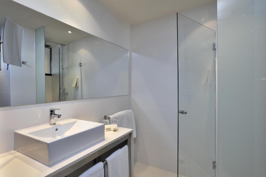 Mūsdienīgs un elegants vannas istabas interjers ar stikla dušu, balto izlietni un lielu spoguli. Vannas istaba izceļas ar tīrām līnijām un minimālistisku dizainu.