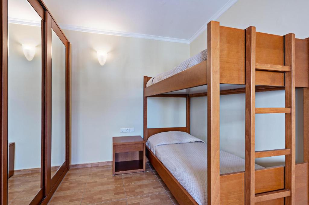Gultas istaba ar divguļamo gultu un spoguļu skapjiem, kas rada modernu un vienkāršu interjeru. Gaisma no sienas lampām piešķir telpai siltumu un komfortu.