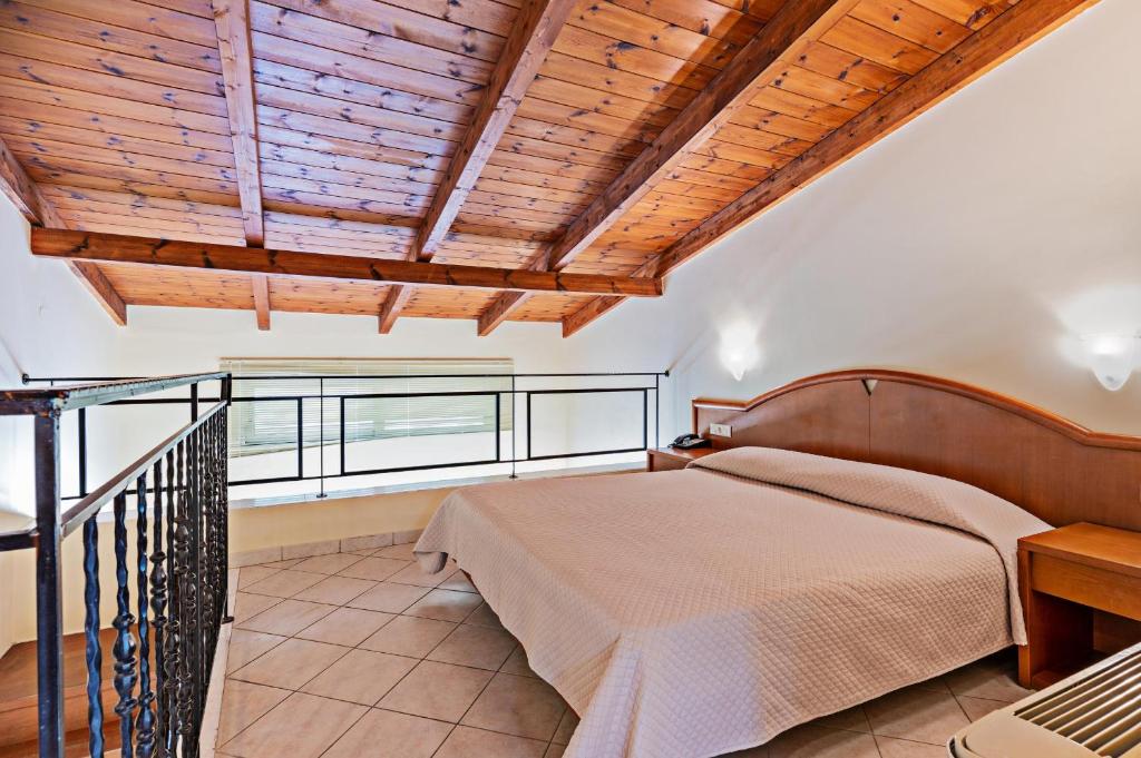 Mūsdienīgs guļamistabas interjers ar augstiem koka griestiem un plašu gultu, kas piedāvā komfortablu atpūtu. Telpā ir elegantas detaļas un dabiska gaisma.