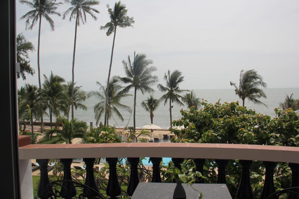 Skats no balkona uz jūru, kur redzami palmas un baseins. Ideāla vieta atpūtai pie ūdens.