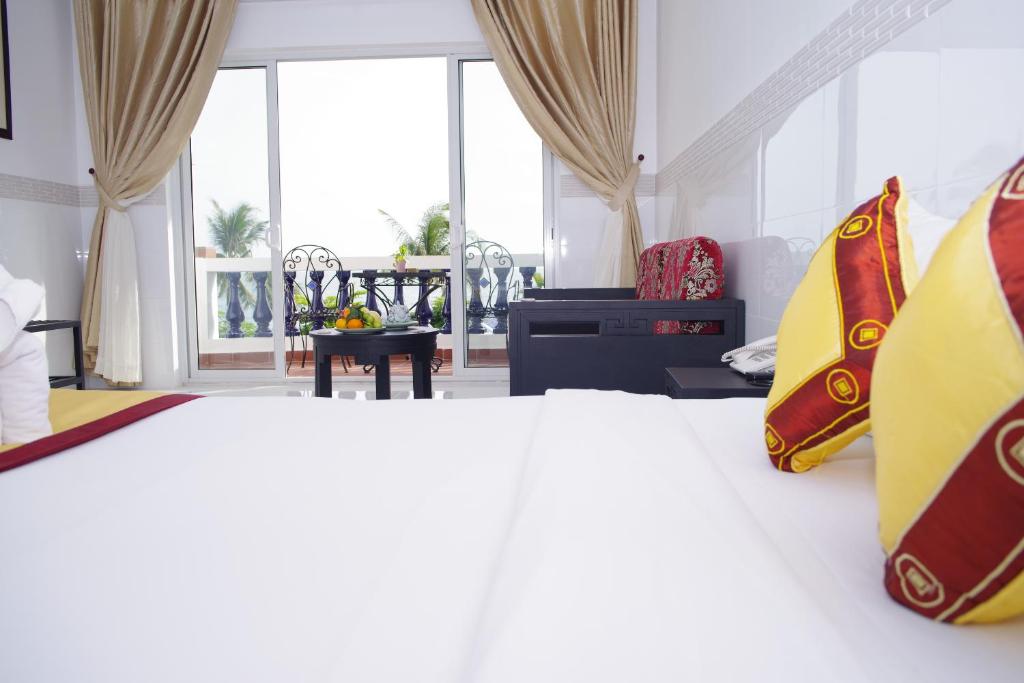 Moderns viesnīcas numurs ar skatu uz terasi, kurā redzama augļu grozs un eleganti mēbeles. Svaigi toņi un gaismas iekārtojums rada relaksējošu atmosfēru.