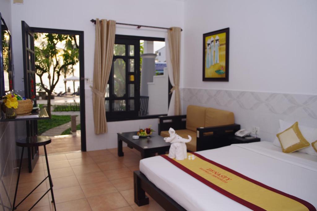 Mūsdienīgs viesnīcas numurs ar izgaismotiem logiem, ērtu dīvānu un dekoratīvu mājdzīvnieku no dvieļiem. Skats uz dārzu un terasi, kas rada patīkamu atmosfēru.