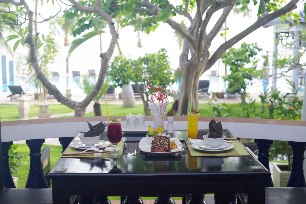 Eleganta galda iestatīšana ar garšīgu ēdienu un dzērieniem, apjozta ar zaļumiem un baseina skatu. Ideāla vieta relaksācijai un baudīšanai.